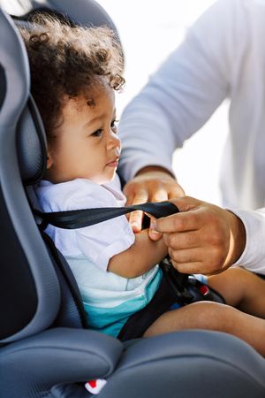 Infant boy being secured in car seat