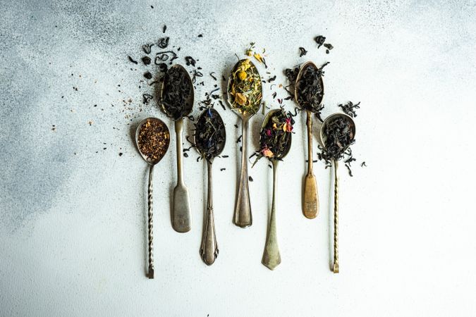 Vintage spoons with loose leaf tea on counter with copy space