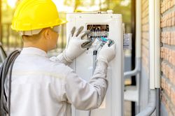 Man in bump cap fixing an electrical machine outdoor