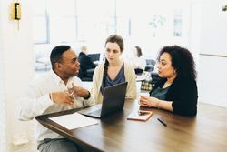 Three colleagues discussing work in an office