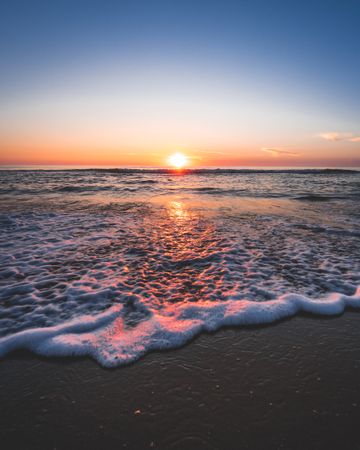 Ocean waves on sandy shore during sunset