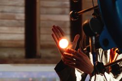 Bright circle of telescope light glows on man’s hand.