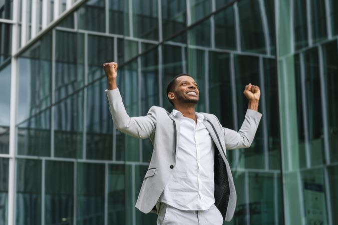 Enthusiastic Black man rejoicing raising hands up