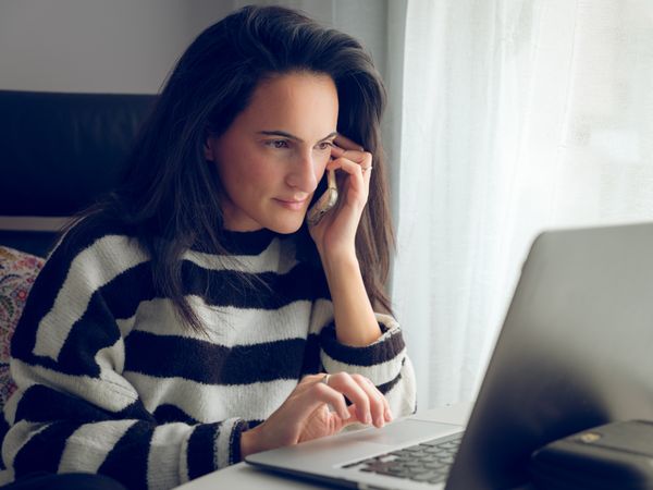 Young female freelancer having phone call and working on