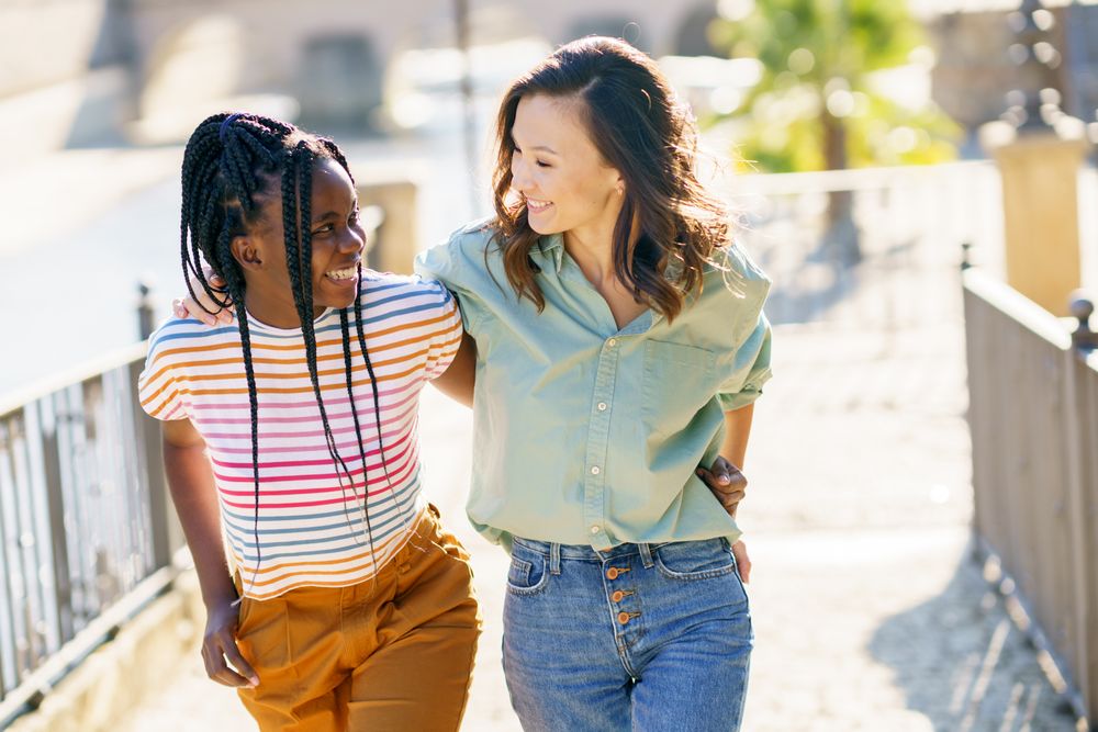Female friends smiling in casual clothing walking up cobble stone path