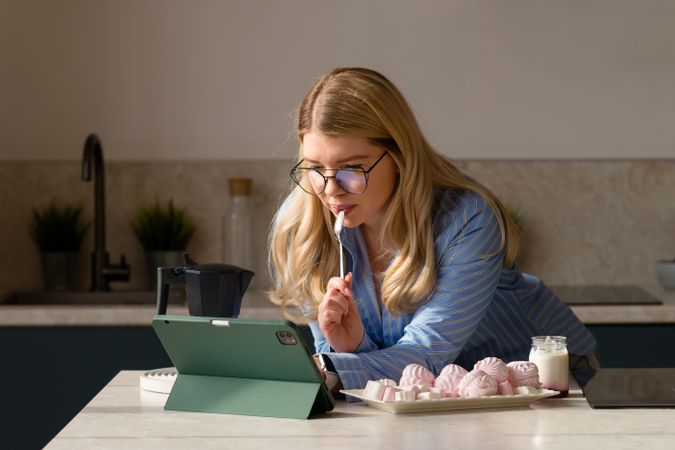 Woman working on tablet in kitchen with breakfast