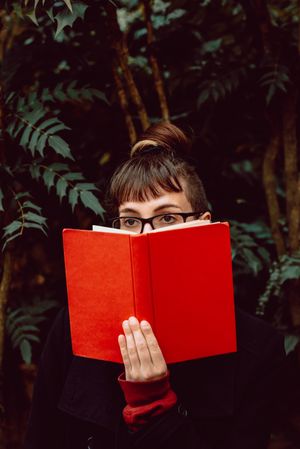 Young woman reading book on bench in park