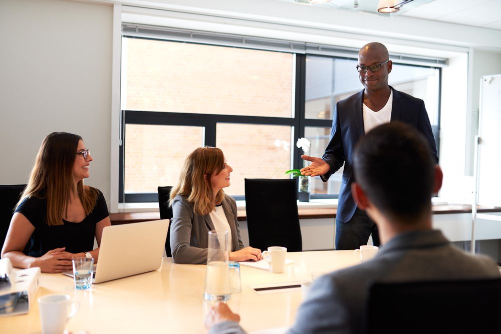 Businessman standing and leading a meeting with smiling colleagues in office