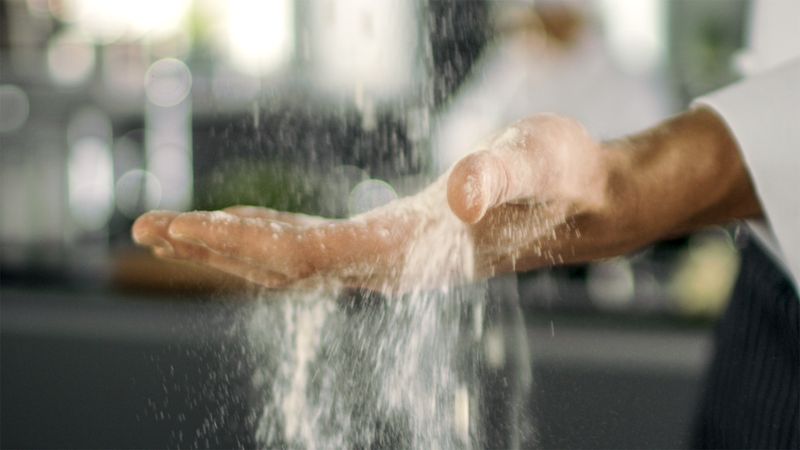 Baker Chef of Famous Restaurant Sifts Flour on His Hand in a Modern Looking Kitchen.