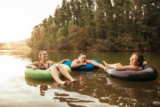 Portrait of happy young friends in inflatable rings floating on lake