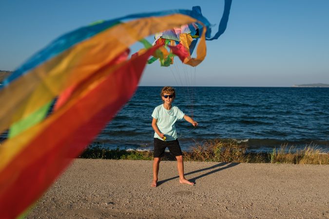 Carefree boy with fluttering kite on beach