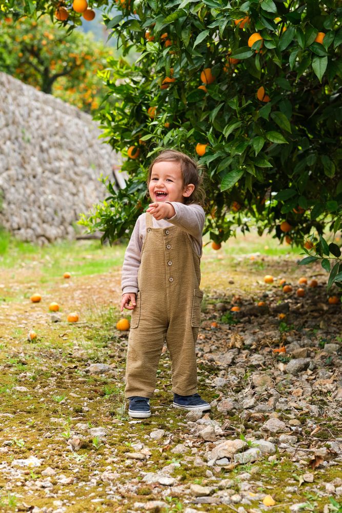 Happy boy showing with finger against orange tree