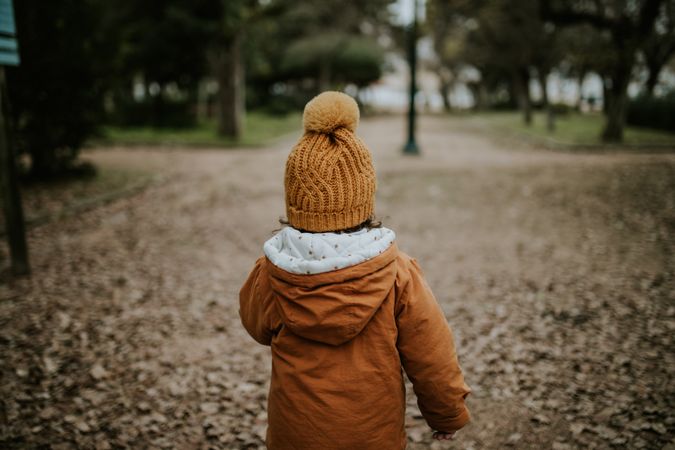 Child in winter clothes walking on path in the park