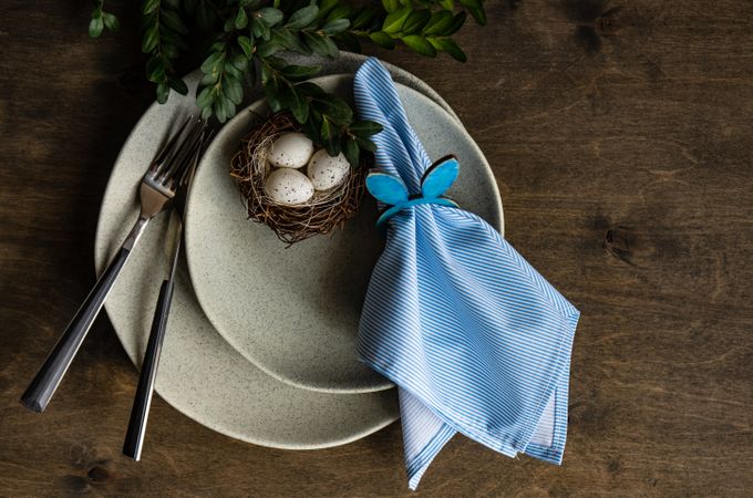Spring table setting with small bird's nest and blue napkin