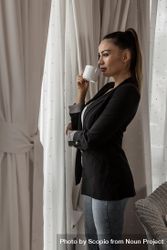 Side view of woman in blazer enjoying morning coffee by the window 5qL3E0