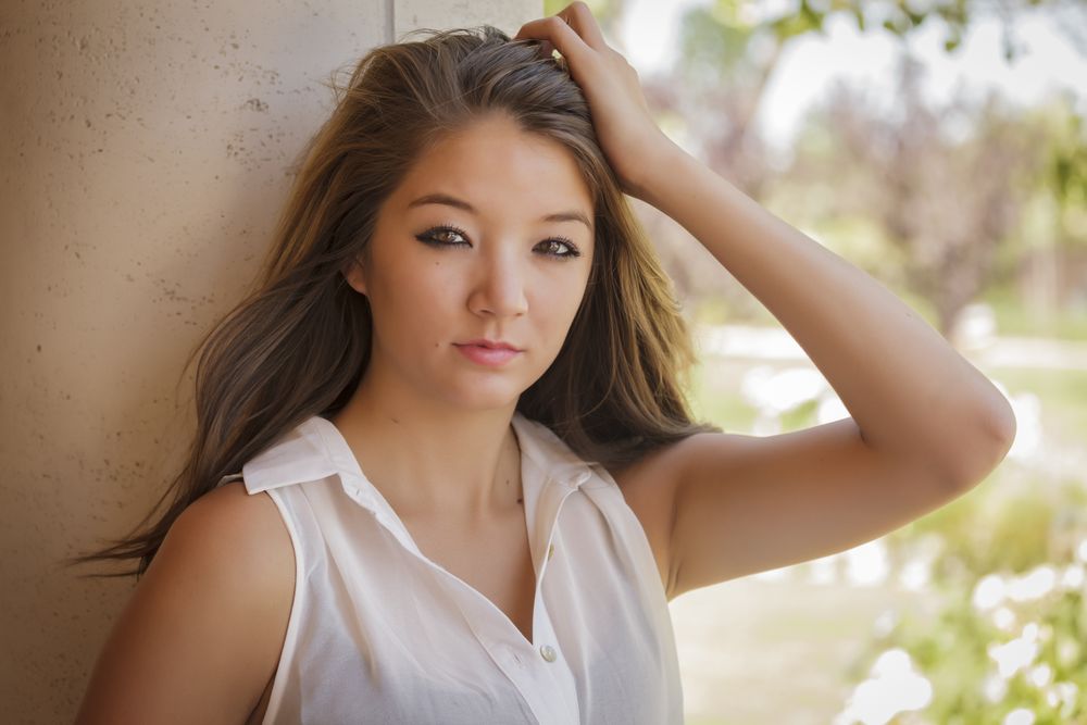 Portrait Of Asian Woman With Hand to Hair Standing Outdoors On Nice Day