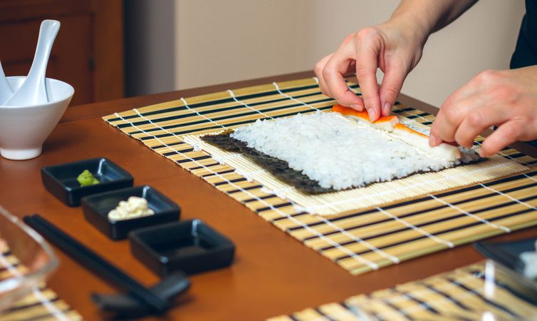 Chef hands placing crab meat on rice to make sushi