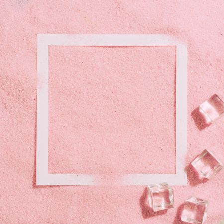 Pink sand with paper square outline and ice cubes