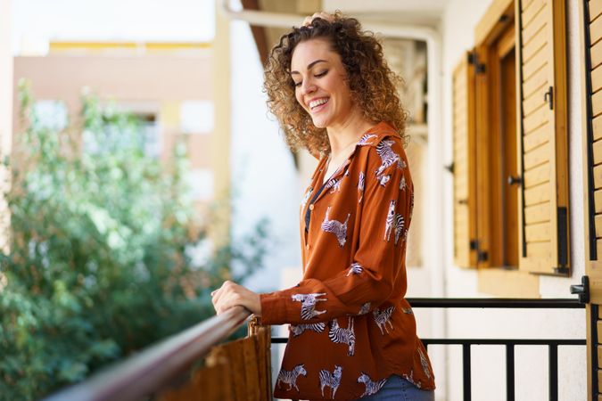 Cheerful young woman standing on balcony