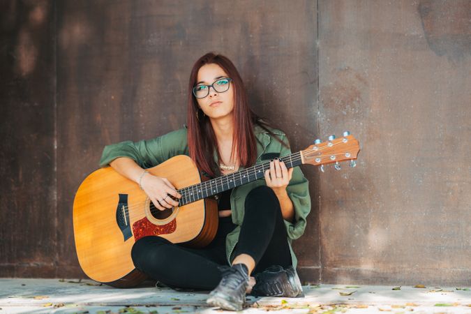 Romantic woman playing guitar leaning on wall