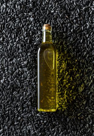 Oil bottle on a pile of sunflower seeds, above view