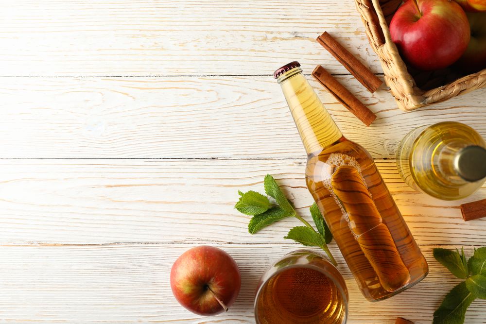 Composition with cider, cinnamon and apples on wooden background