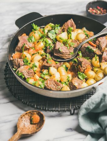 Braised beef stew with potatoes, carrots and parsley, with wooden spoon, selective focus