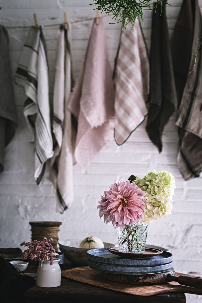 Table with flowers in vase on trays near towels hanging on thread