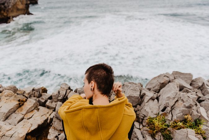 Woman in yellow hoodie on stony shore
