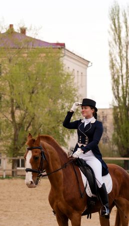 Rider saluting on horseback in city equestrian arena