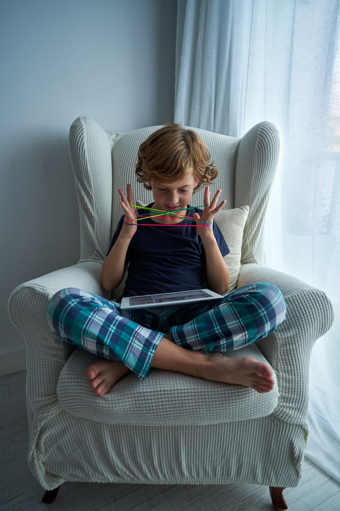 Content boy watching video while playing string game