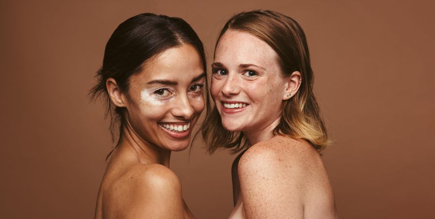 Smiling young women with beautiful natural skin on brown background
