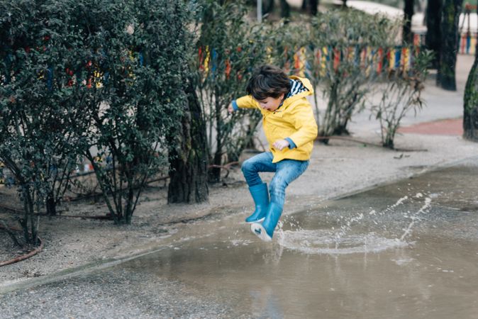 Happy kid jumping on puddle