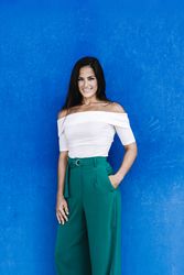 Portrait confident smiling young woman against a blue wall