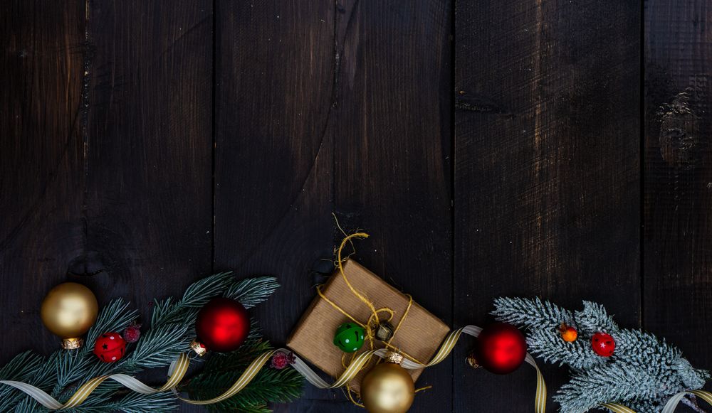 Top view of Christmas gift wrapped in brown paper surrounded by baubles and fir