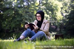 Woman sitting in grassy forest with book 5qzLa4