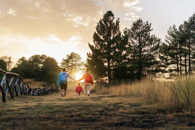 A man and woman are walking with their child in a field - candid family moment