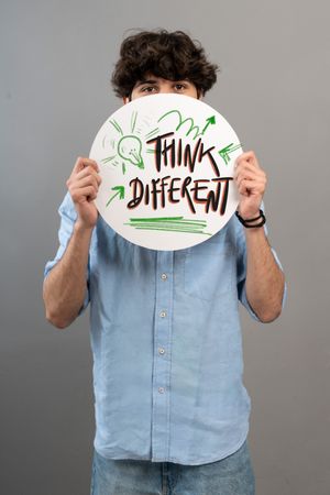 Young man holding a sign with the message Think Different for innovation and creativity