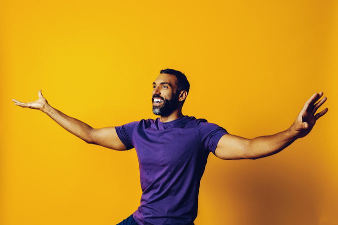 Happy Black man in yellow studio with arms open to the side