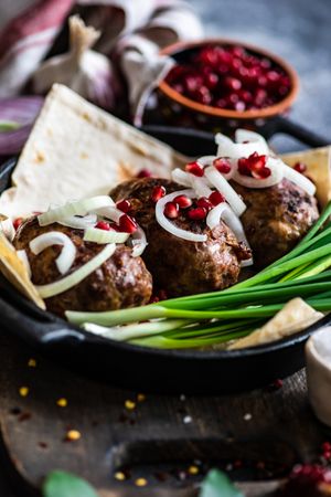 Close up of Georgian plate of abkhazura meat cutlets with pomegranate seeds and onions