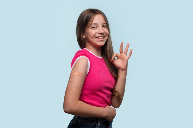 Girl with OK hand gesture after receiving vaccination
