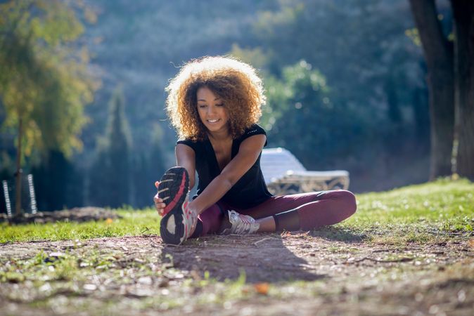 Happy woman warming up legs in park