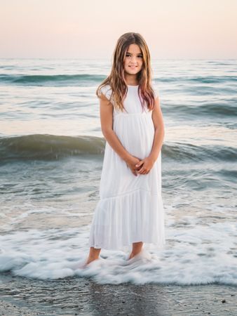 Smiling girl standing on seaside among waves