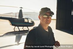 Helicopter pilot in cap and sunglasses inside hangar 0LQaD5