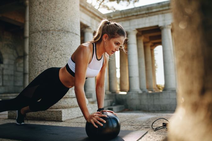 Woman in fitness clothes training with a medicine ball