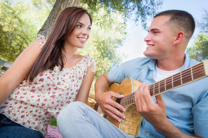 Male Playing Guitar for His Girlfriend in the Park.