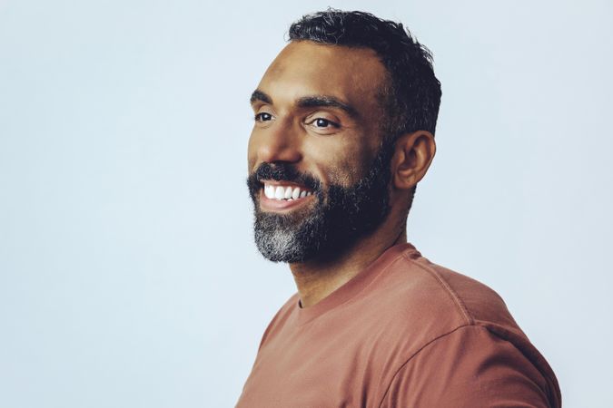Portrait of laughing Black male looking away in grey studio