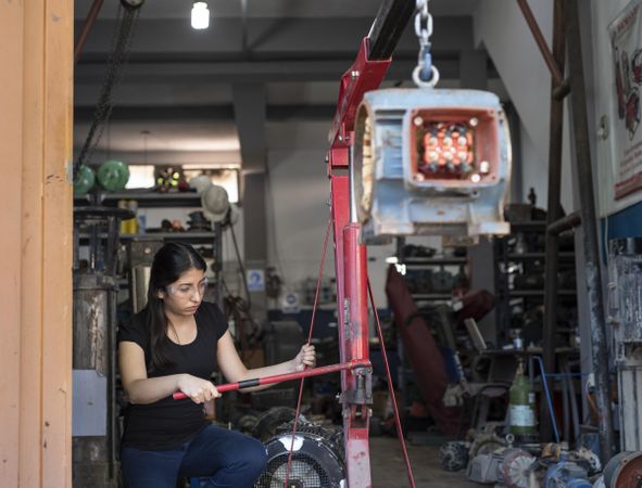 Woman wearing goggles working on heavy machine