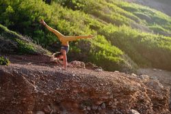 Anonymous female athlete practicing yoga in handstand in nature