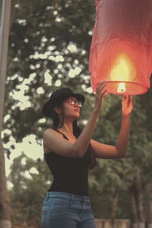 Woman with hat about to fly a lit lantern